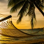 Hammock silhouette with palm trees on a beautiful beach at sunse
