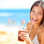 Beach woman drinking cold drink beverage having fun at beach par